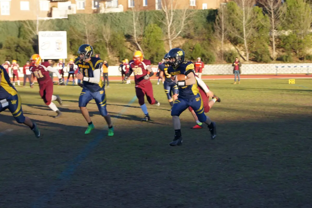 Jugadores de tackle con casco y hombreras durante un partido de fútbol americano de los Wildcats